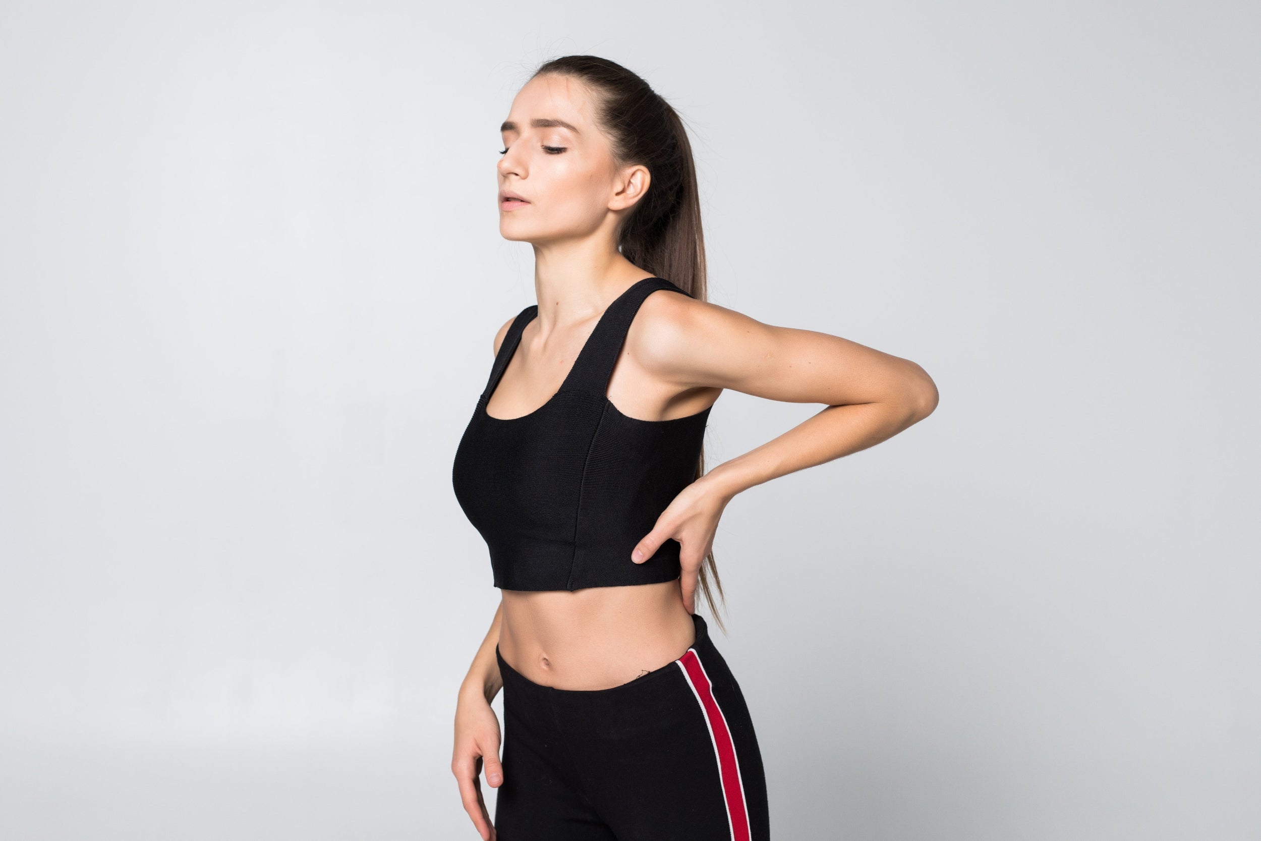 Woman in black athletic wear against a light gray background